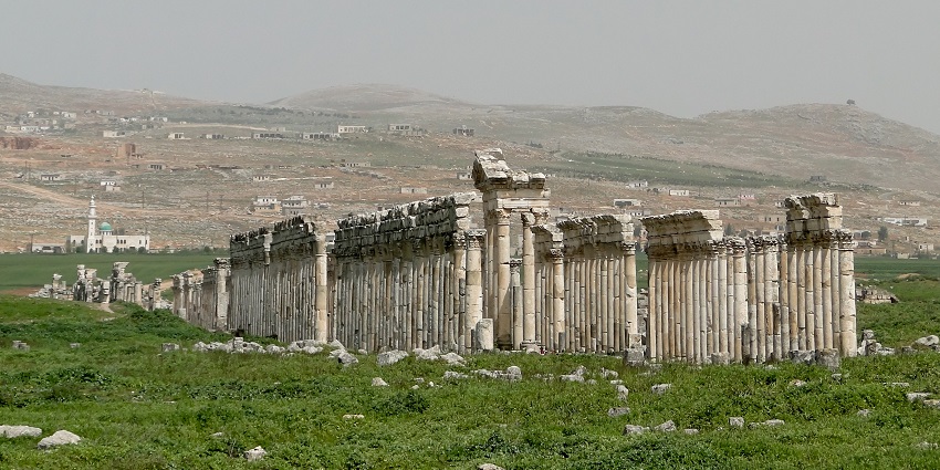 Apamea with ruined architecture, multiple tall broken pillars and buildings in the back