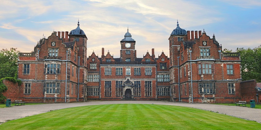 Jacobean-style Aston Hall with symmetrical red-brick façade and manicured gardens.