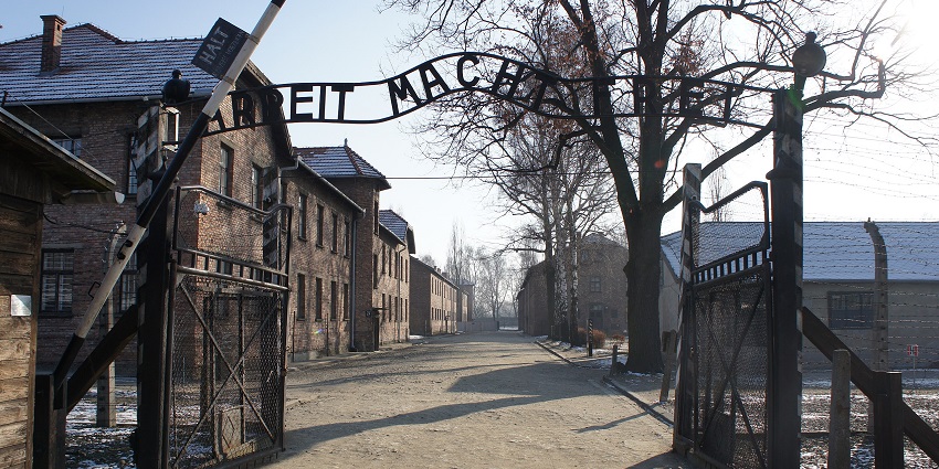 Entrance gate of Auschwitz-I with old building structures and a motto written on the gate