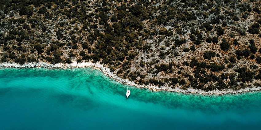 Aerial view of rocky coastline with clear blue water and lush greenery surrounding it