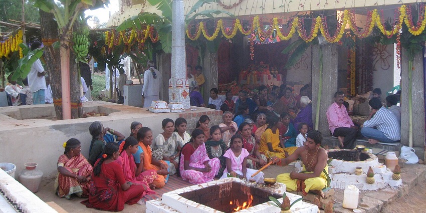 Devotees sitting at the Lord Sri Thimmaraya Swamy Temple, featuring traditional architecture and a peaceful rural setting.