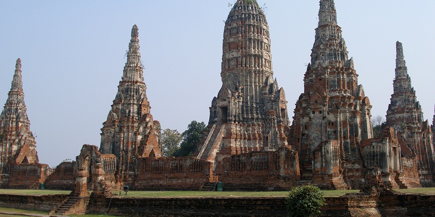 Ancient brick temple ruins with tall towers and intricate carvings under a clear sky, one of the historical places in Thailand.