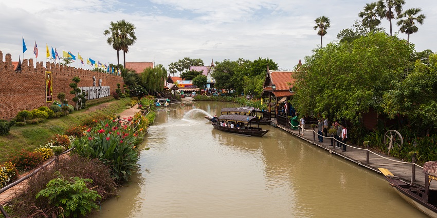 Ayutthaya in Thailand, with people in a boat on a brown water body, and colourful flowers