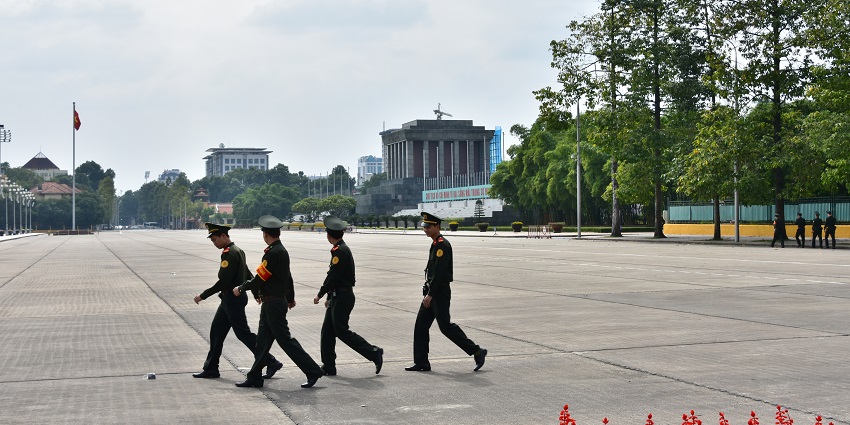 A view of Ba Dinh Square, in Hanoi, with four officers in uniform walking across the square.