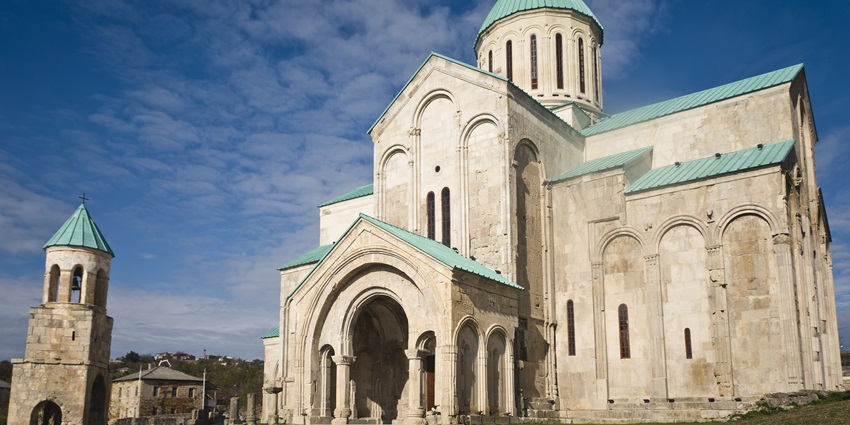 Bagrati Cathedral, a hilltop monument in Georgia, has a green roof and stone architecture.
