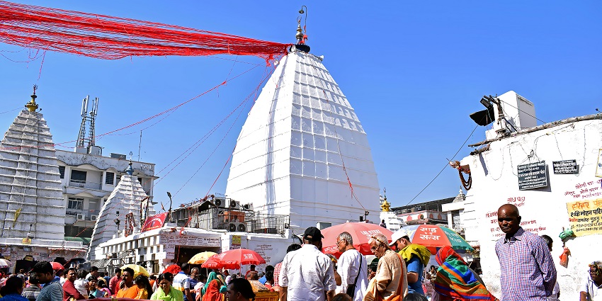 A large crowd gathered at the white temple complex during a vibrant religious festival.