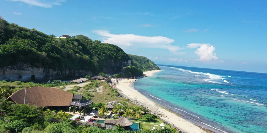 A scenic view of Seminyak Beach, waves lapping gently under cloudy blue skies, one of the top places to visit in Indonesia in December.