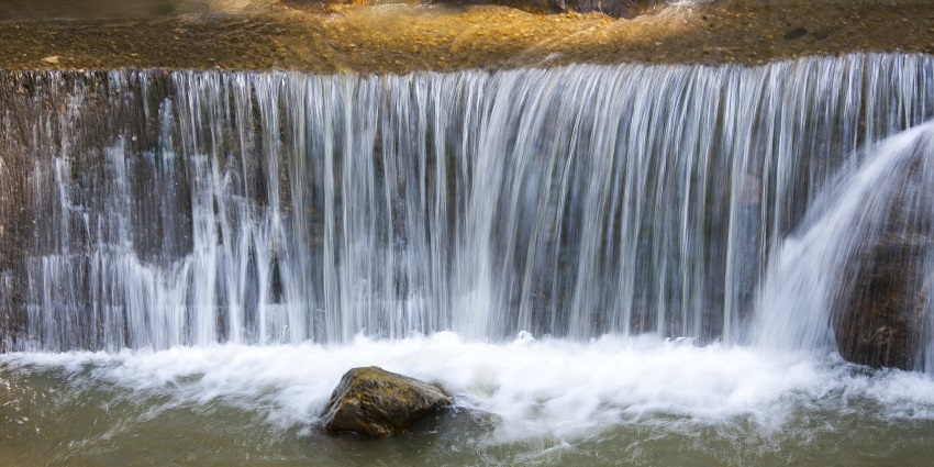 Ban Jhakri Falls in Gangtok, showing cascading water over rocky ledges into a shallow pool.