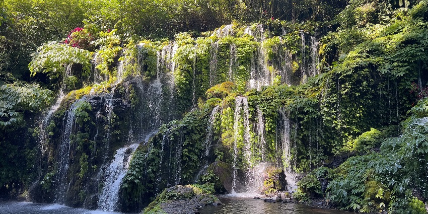 Multi-tiered Banyu Wana Amertha waterfall cascading over mossy rocks, one of the top places to visit in Bali in February.