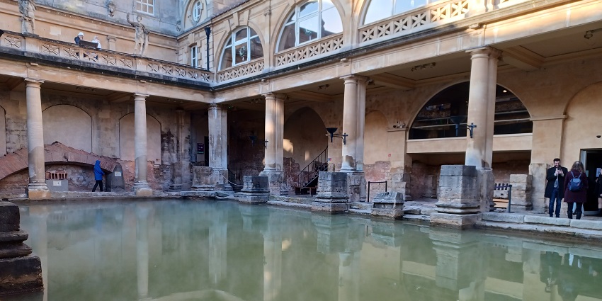 Bath Roman baths with greenish water, people visiting the bath and multiple pillars