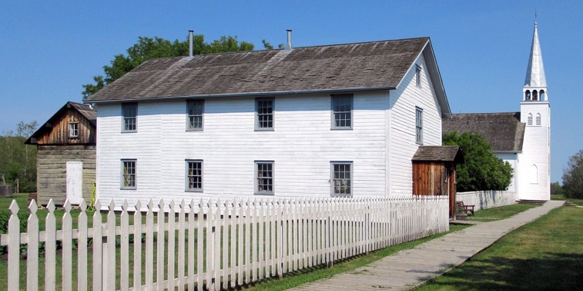 Batoche National Historic Site with white buildings and a cemetery surrounded by greenery