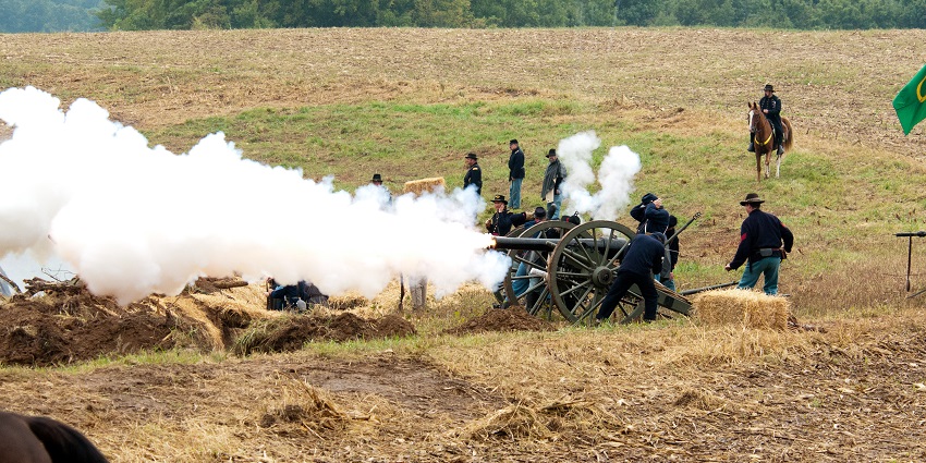 Battle of Lexington State historic site with people firing the old cannons and trees in the back