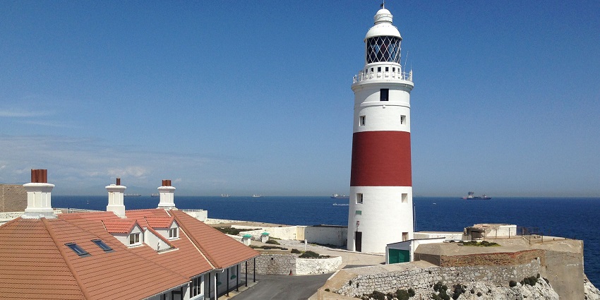 White-red Europa Point Lighthouse overlooking the Strait of Gibraltar with Africa in view.