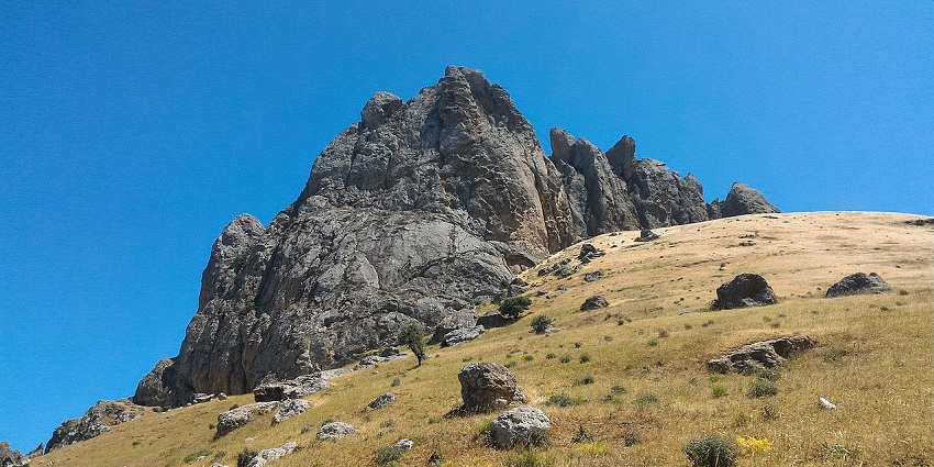 A towering rock formation resembling five fingers, rising dramatically from the Caspian plain.