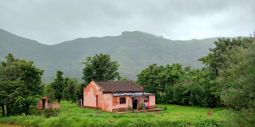 Image with scenic view towards Kenjalgad fort with green hills and rugged terrain below.