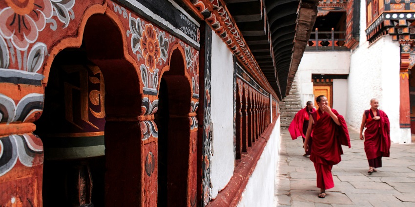 Monk walking in monastery corridor, reflecting why Is Bhutan Worth Visiting today