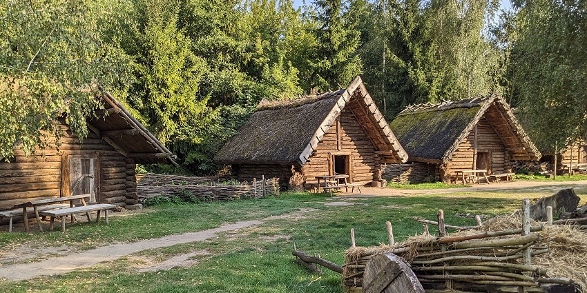 Biskupin Archaeological Site with old wooden houses and a cart surrounded by greenery
