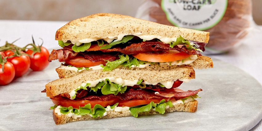 Layered sandwich with vegetables, chutneys, and masala spices served on white bread slices.

