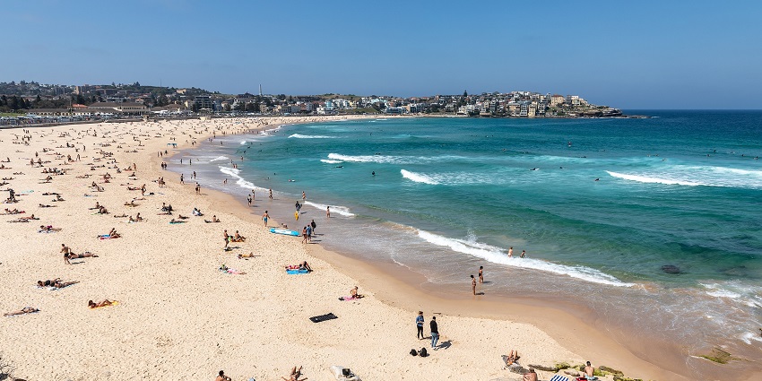 The blue waters of Bondi Beach were clicked on a sunny day with many tourists relaxing around.