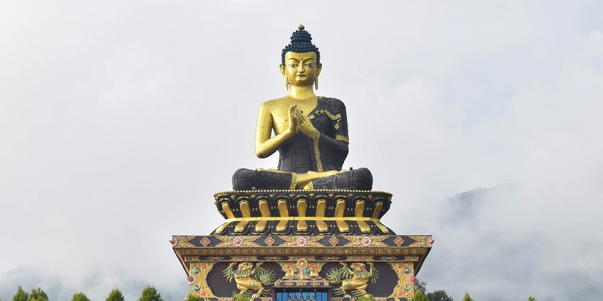 A grand seated Buddha statue on an ornate platform overlooks green lawns, amongst the top places to visit in Sikkim in October.