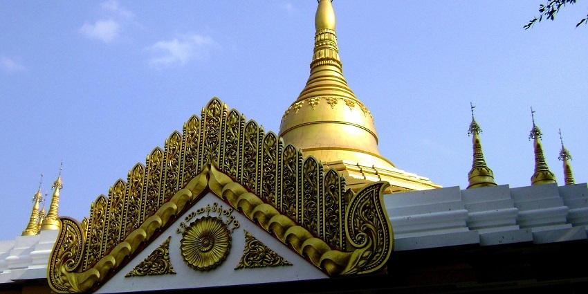 An image of the Botataung Pagoda complex with a golden stupa under the clear sky.