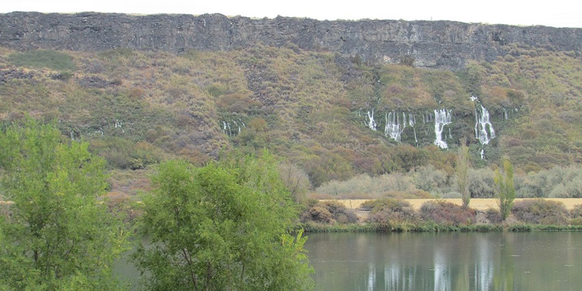 Box Canyon Springs reserve with a large still water body, trees and distant waterfalls