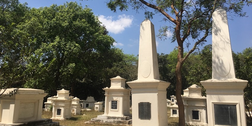Restored gravestones at British Garrison Cemetery surrounded by greenery.
