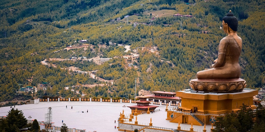 Buddha Dordenma with brass architecture, people visiting the place and distant buildings.