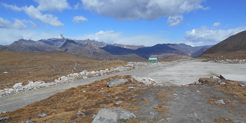 Bum la Pass in Tawang with a distant small building, and mountains, one of the most stunning places to visit in Tawang in January.