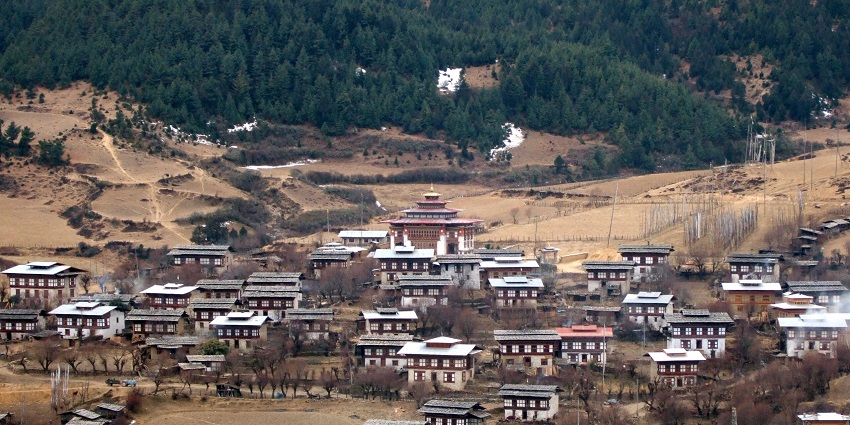 Bumthang district with traditional Bhutanese architectural houses and brown trees.