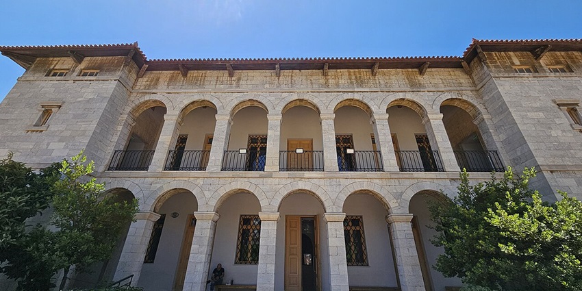 Two-story stone building with arched columns, wooden doors, and a tiled roof, one of the most beautiful historical Places in Athens Greece.