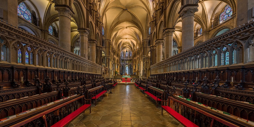 The interior of Canterbury Cathedral has with unique ceiling, warm lighting and vibrant windows.
