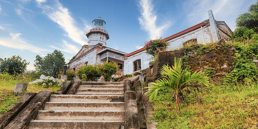 Black iron entrance gate of Cape Bojeador lighthouse with tall lighthouse building