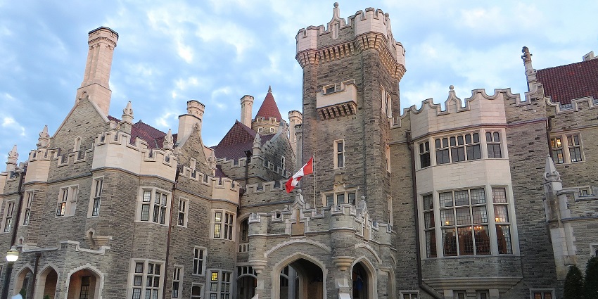 A grand stone castle with turrets, and a Canadian flag, on the list of monuments in Canada