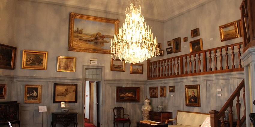 Inside a Museum with paintings on the walls, a wall hanging illuminated in the centre, one of the most iconic historical places in Corfu.