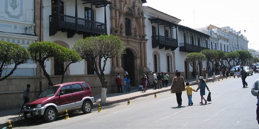 A view of Casa de la Libertad with visitors at the entrance and cars parked along the street.