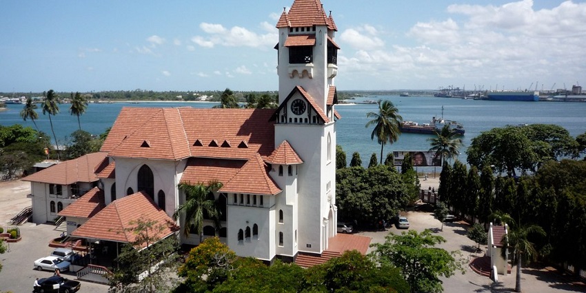 Historic white Azania Front Church with tall steeple framed against a partly cloudy blue sky in Dar es Salaam.
