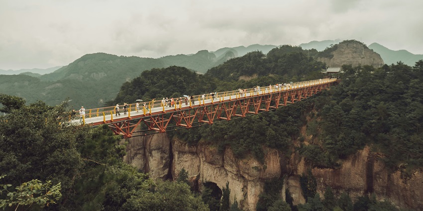 Chagzam Bridge, a traditional bridge over the river, buildings at both ends, and green trees