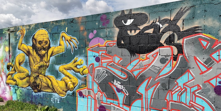 Graffiti on the wall with vibrant, unique designs on the wall and clouded blue sky.