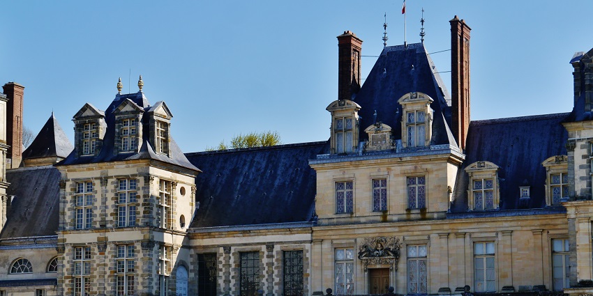 Elegant French château with grand staircase, tall chimneys, and ornate Renaissance design.