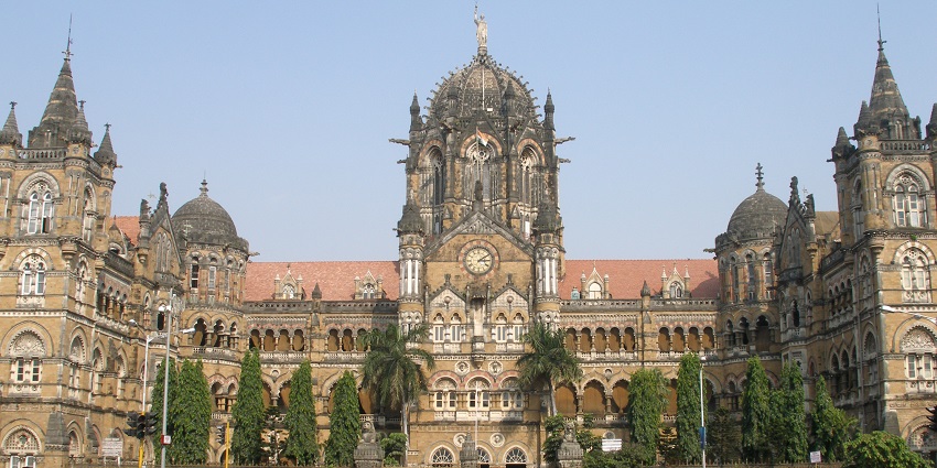 Victorian-era railway station with ornate carvings, glass, and spires in Gothic style.