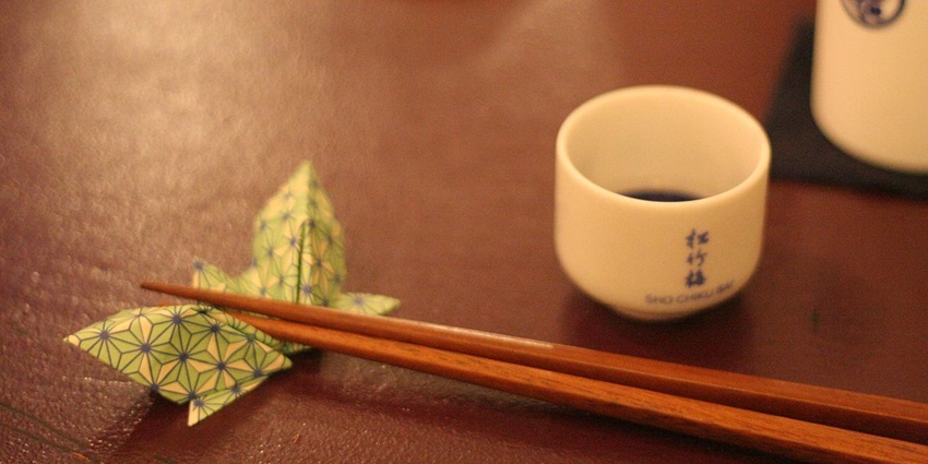 A close-up of colourful chopsticks with Japanese patterns displayed in an open wooden box.