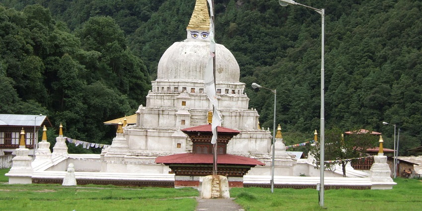 Chorten Kora in Bhutan with a white architectural structure, tall white flags, and street lights.