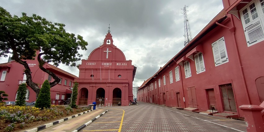 Red exterior of Christ Church with white cross and Dutch-style architecture.