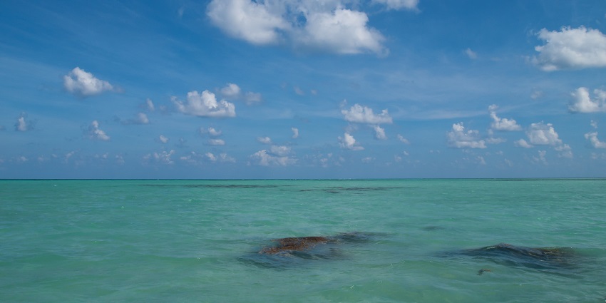 The blue Andaman Sea stretches to the horizon under a wide sky with scattered clouds