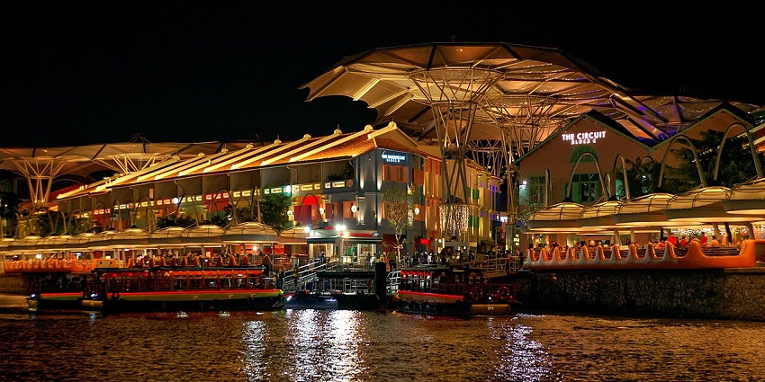 Clarke Quay in Singapore, at night, with colourful lights reflecting on the river, one of the best places to visit in Singapore in September.
