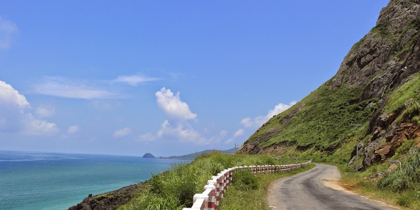 Côn Đảo Island coastline with rocky shores, dense greenery, and bright blue waters.