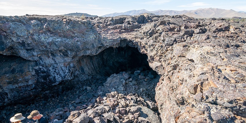 Craters of the moon caves monument with cave entrances, rocks and people visiting.
