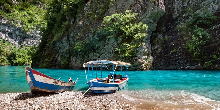 Things to do in Albania include embarking on a scenic boat ride through Komani Lake, surrounded by towering cliffs.