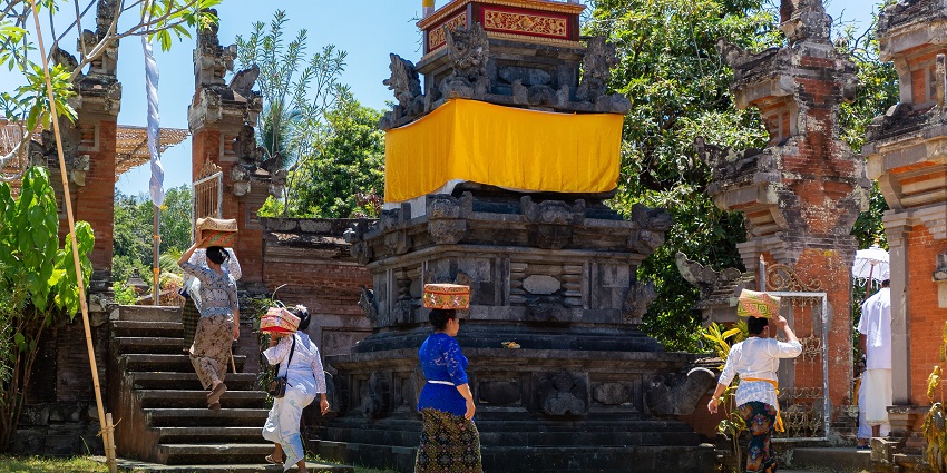 Bali, Indonesia: Balinese people carrying goods into a temple in baskets on their heads in preparation for an upcoming festival
